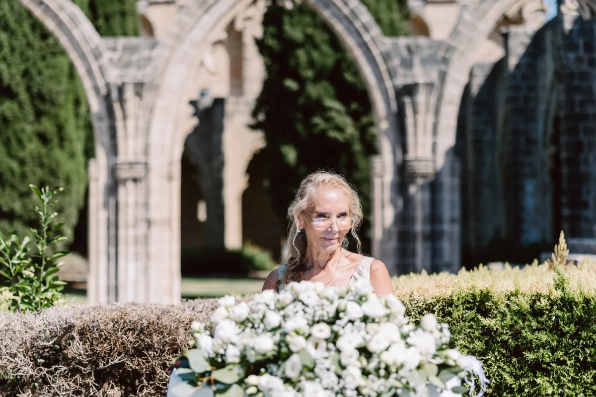 Tören çiçeklerinin ardında oturan davetli, Bellapais Manastırı kemerleri — Mert Gardiyanoğlu Photography