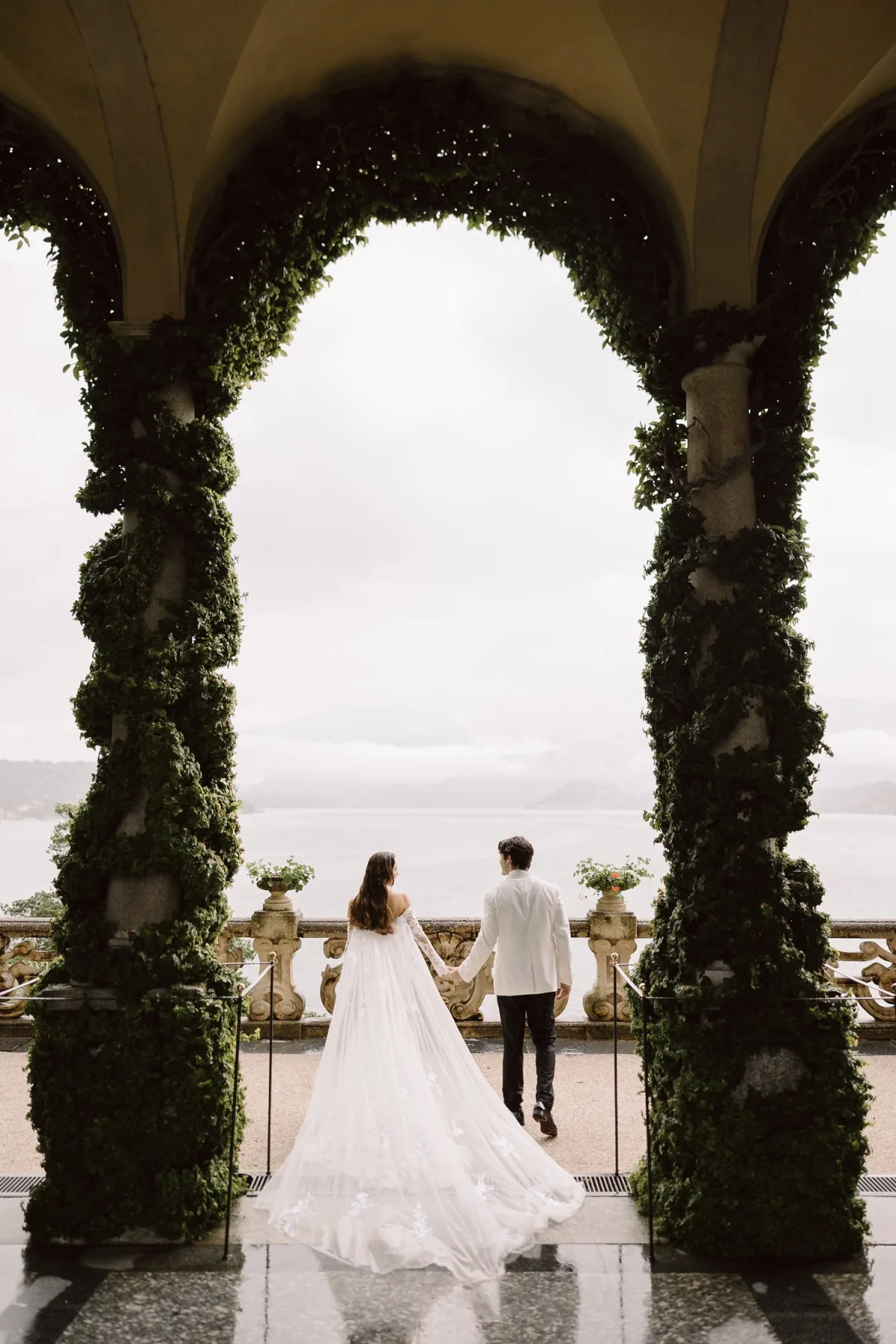 Destination wedding photographer — couple under a greenery arch above Lake Como, Italy
